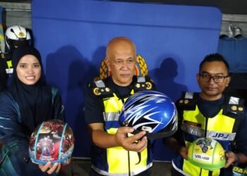 AMAN Shah Hashim (tengah) menunjukkan jenis-jenis topi keledar yang tidak memenuhi spesifikasi dan ditukar orang ramai dalam Program Penukaran Topi Keledar JPJ Kedah di Tasik Darul Aman, Jitra.