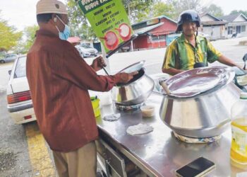 JAMALUDIN Alaudeen melayan pelanggan yang membeli bubur gandum digerainya di Teluk Intan. – UTUSAN/AIN SAFRE BIDIN