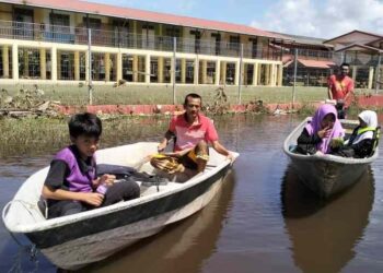 ROSLI Abdul Ghani (kiri) bersama Suhanuddin Yusof mengemudi bot untuk menghantar anak-anak mereka ke SK Bendang Pak Yong, Tumpat, Kelantan semalam. – UTUSAN/ROHANA ISMAIL