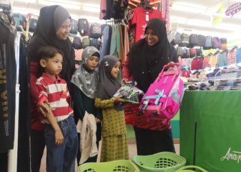 MUZALIZA Musa (kanan) menyantuni salah seorang murid yang juga penerima sumbangan bagi membeli peralatan dan kelengkapan persekolahan di sebuah pasar raya di Nilai, Seremban ini.-UTUSAN/NUR SHARIEZA ISMAIL.