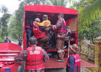 ANGGOTA Bomba giat membantu menyelamatkan penduduk yang terjejas dengan banjir di Pasir Puteh, Kelantan semalam.-IHSAN JBPAM.