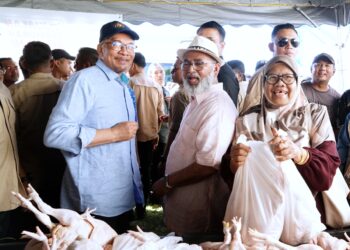 ANWAR Ibrahim (kiri) dan Syed Abu Hussin Hafiz Syed Abdul Fasal pada program Jualan Termurah Madani barangan basah dan kering di padang Taman Klebang Restu, Ipoh hari ini. - UTUSAN/ZULFACHRI ZULKIFLI