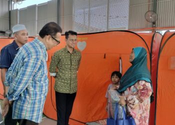 MASRIFAH MOHAMMAD (kanan) ketika ditemui Pengerusi Jawatankuasa Hal Ehwal Agama Negeri Johor, Mohd Fared Mohd Khalid (dua dari kanan) di pusat pemindahan sementara PPS Sekolah Kebangsaan Bukit Kuari di Ayer Hitam semalam.