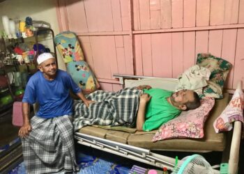 SULAIMAN Omar (kiri) menemani Ismail yang sakit kronik di rumahnya di Kampung Telaga Gajah, Banggol Kota Bharu, Kelantan.- UTUSAN/ROSLIZA MOHAMED