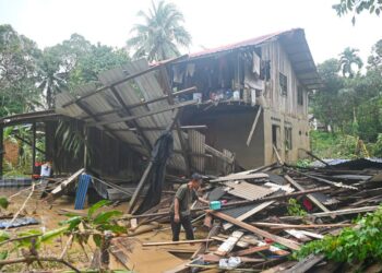 SEORANG penduduk mengambil barangan yang boleh diselamatkan selepas sebahagian rumahnya runtuh dalam kejadian banjir besar di Kampung Shukor, Hulu Dungun, Terengganu, semalam. - UTUSAN/PUQTRA HAIRRY