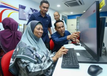 MOHD. Azlan Helmi (kanan) membantu seorang wanita mendaftar dalam Pangkalan Data Utama menerusi komputer di Pusat Ekonomi Digital di Ipoh hari ini. - UTUSAN/MUHAMAD NAZREEN SYAH MUSTHAFA