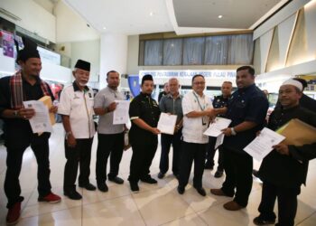 AHMAD Yakqub Nazri (dua dari kanan) menyerahkan surat bantahan pembinaan asrama warga asing di Teluk Kumbar kepada wakil Ketua Menteri, Zahar Zainul di perkarangan Komtar, George Town, Pulau Pinang, hari ini.