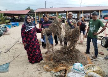 TUMINAH Kadi melihat jaring milik nelayan Mohd. Muszairi Mohamed yang rosak di Pantai Puteri, Melaka. UTUSAN/AMRAN MULUP