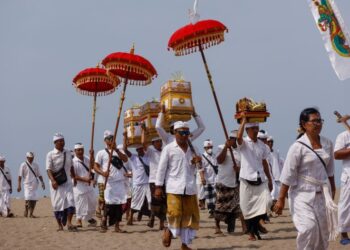 Anggota masyarakat Hindu pulang dari upacara di pantai di daerah Kerobokan di pulau peranginan Bali, Indonesia