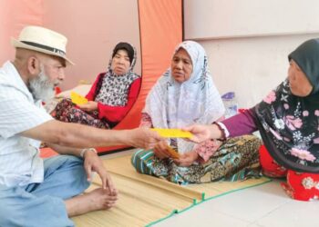 SYED Abu Hussin Hafiz Syed Abdul Fasal menyampaikan sumbangan kepada tiga beradik dan ahli keluarga mereka yang berteduh di Dewan Matang di Bukit Gantang, Perak. - UTUSAN/WAT KAMAL ABAS