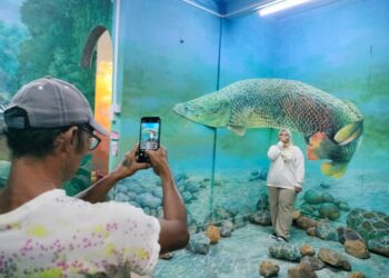 . MAISARAH Mohd. Azmaharul bergambar berlatarbelakangkan ikan kelisa di Rumah Seni di Jalan Penghulu Kasim Kluang.