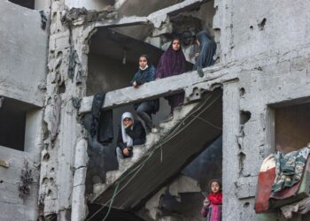 WANITA dan kanak-kanak Palestin berdiri di struktur bangunan yang rosak teruk akibat dibedil bom tentera Israel dalam serangan udara di kem pelarian Rafah, selatan Gaza. -AFP