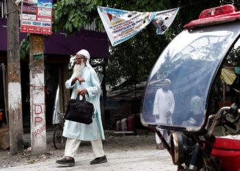 PENDUDUK berjalan melepasi sebuah tuk tuk di daerah Dhubri, Assam di India. - REUTERS