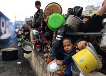 KANAK-kanak Palestin menunggu untuk mengutip makanan di pusat sumbangan di kem pelarian di Rafah di selatan Gaza pada 23 Disember 2023.-AFP