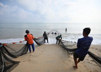 PENDUDUK kampung bergotong-royong melakukan aktiviti menarik pukat darat di  Pantai Mengabang Lekor, Batu Rakit, Kuala Nerus semalam. - UTUSAN/PUQTRA HAIRRY ROSLI