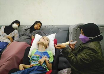 NURIZRIN Ishak (kanan) memberikan susu kepada anaknya, Mohammad Fitri yang menghidap Cerebral Palsy ketika ditemui di rumahnya di Flat Taman Semarak, Nilai, Seremban.-UTUSAN/NUR SHARIEZA ISMAIL