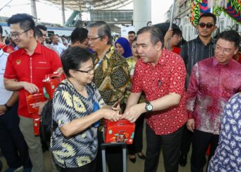 ANTHONY Loke Siew Fook  menyantuni penumpang yang tiba dari Kuala Lumpur pada Pelancaran Sistem Pembayaran Terbuka KTMB di Stesen Keretapi Ipoh hari ini. - UTUSAN/MUHAMAD NAZREEN SYAH MUSTHAFA