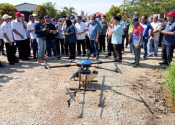 MOHAMAD Sabu mengendalikan dron ketika lawatan ke projek penanaman padi di Kampung Sawah Ring, Tangkak.