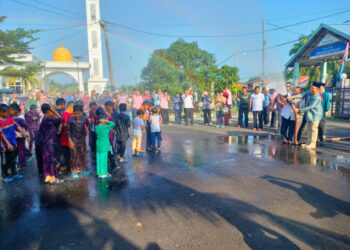 HASNI Mohammad (kanan) ‘memandikan' kanak-kanak dengan membuat semburan air kepada peserta Program Berkhatan ‘Gerbang  Remaja’ di Komplek Penghulu Mukim Sungai Pinggan, Pontian.