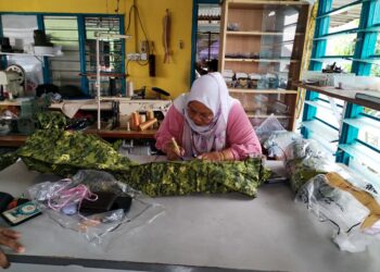 ALIMAH Jaafar menyiapkan uniform yang tidak sempat dijahit disebabkan bekalan elektrik terputus secara tiba-tiba di sekitar Pekan Sungai Udang, Kem Terendak dan Tangga Batu, Melaka. - UTUSAN/AMRAN MULUP