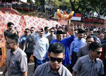 ANWAR Ibrahim dan Ab. Rauf Yusoh mengangkat tangan kepada orang ramai yang berhimpun di sepanjang laluan ke Jonker Walk, Banda Hilir, Melaka. - UTUSAN/AMRAN MULUP