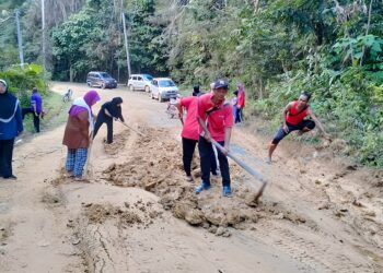 SEBAHAGIAN guru dan penduduk sedang membaik pulih kawasan jalan yang rosak di Kampung Bukit Mat Daling di Jerantut, Pahang. - UTUSAN/HARIS FADILAH AHMAD