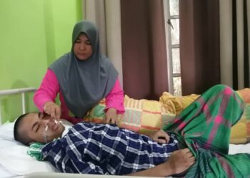 WAN Murni Wan Ngah menemani anaknya, Muhammad Amirul Nazmi Sam yang terlantar lumpuh di Kampung Jaba, Ajil, Hulu Terengganu. - UTUSAN/NOOR HAYATI MAMAT