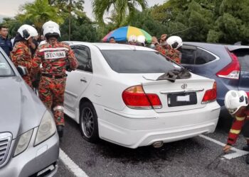 ANGGOTA bomba membuka pintu kereta yang berkunci di kawasan tempat letak kenderaan HRPB Ipoh hari ini.  - UTUSAN/IHSAN JBPM