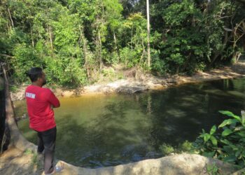 SEORANG penduduk melihat air Sungai Ketil bertukar menjadi hitam di kawasan rekreasi Rimba Wangi di Taman Wangi, Gua Musang, Kelantan.-UTUSAN/AIMUNI TUAN LAH