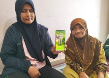 NORFATIHAH Jusof (kiri) bersama mentuanya menunjukan gambar arwah suami ketika ditemui di Kampung Baru Jalan Malaysia, Jeli, Kelantan-UTUSAN/ROHANA ISMAIL.