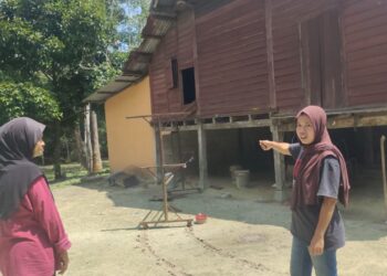 NORHAYATI Maasim (kanan) menunjukkan lokasi dinding papan rumah yang diumpil penyamun dalam kejadian di Kampung Air Besar, Kepis Ulu, Kuala Pilah awal pagi tadi.-UTUSAN/NOR AINNA HAMZAH.