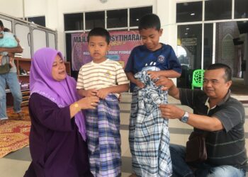 MOHAMAD  Zaki Yaacob (kanan) bersama isterinya membantu memakaikan kain pelikat kepada kedua-dua anaknya yang menyertai Program Sunathon Asnaf Hijraa Kota Bharu 2024 di Masjid Mukim Peringat, Kelantan. UTUSAN/ ROSMIZAN RESDI