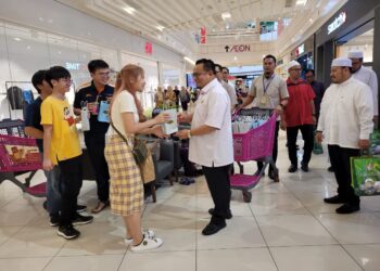 HILMI Abdullah (kanan) mengagihkan 'woven bag' kepada para pengunjung di sebuah pasaraya di Lembah Sireh, Kota Bharu, Kelantan hari ini. UTUSAN/MUSTAQIM MOHAMED