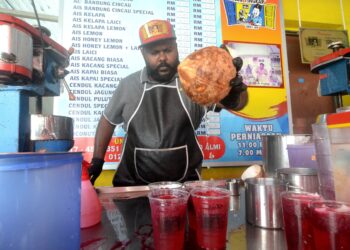 MOHD. Almi Seeni Mohamed menunjukkan cara-cara untuk menyediakan minuman ais tingkap atau air sarbat di gerainya di Lebuh Tamil, George Town, Pulau Pinang.-UTUSAN/IQBAL HAMDAN