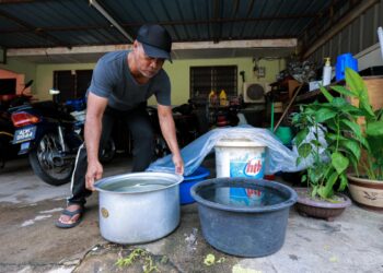 ZAINAL Abidin Ismail mengangkat bekalan air bersih yang diperoleh dari lori tangki air LAP di rumahnya di Kampung Teluk Dalam di Pulau Pangkor. - UTUSAN/ASLIZA MUSA