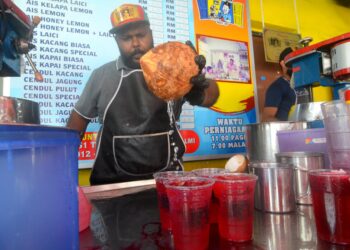 MOHD. Almi Seeni Mohamed menunjukkan cara-cara untuk menyediakan minuman ais tingkap atau air sarbat di gerainya di Lebuh Tamil, George Town semalam. – UTUSAN/IQBAL HAMDAN