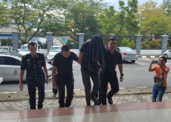 TERTUDUH diringi anggota polis ketika hadir di Mahkamah Sesyen Seremban, Negeri Sembilan, hari ini .- UTUSAN/NUR SHARIEZA ISMAIL