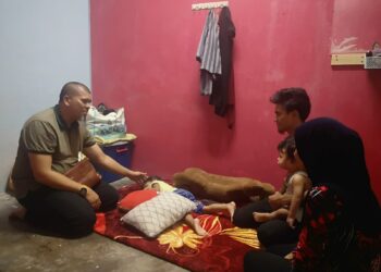 MOHD. Bajuri Abjat (kiri) menyantuni Muhamad Syafiq dan Nurliyana di bilik sewa mereka di rumah kedai di pekan Nilai, Seremban.-UTUSAN/NUR SHARIEZA ISMAIL.