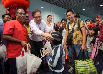 ANTHONY Loke menyerahkan cenderahati kepada penumpang Batik Air Kuala Lumpur - Sibu di KLIA Terminal 1, Sepang. -UTUSAN/FAISOL MUSTAFA