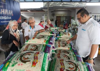 Hassan Karim (tengah) melihat bekalan beras yang akan dijual menerusi Program Jualan Kasih Sayang Bergerak di Dewan Komuniti Taman Desa Cemerlang Perdana, Pasir Gudang, Johor Bahru, hari ini.