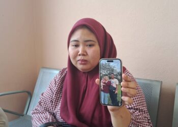 NURHAFIZAH Ahmad Zamri menunjukkan gambar kenangannya dan anak bersama arwah suami yang maut selepas kereta dihempap dahan pokok dalam kejadian di Jalan Hutan Kampung, Kampung Bohor di Alor Setar.