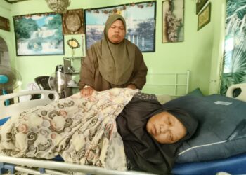 NUR Amalina Nabila Awang Lah (kiri) menguruskan ibunya yang terlantar sakit akibat serangan angin ahmar di di Kampung Pulau Semut, Kedai Mulong, Kota Bharu, Kelantan.- UTUSAN/YATIMIN ABDULLAH