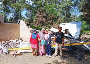 SARINA Abd. Ghani (dua dari kiri) bersama keluarganya di hadapan rumah yang musnah terbakar di Kampung Pagi, Ulu Tembeling, Jerantut, Pahang. - UTUSAN/HARIS FADILAH AHMAD