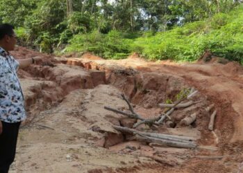 MOHD. Syahbuddin Hashim meninjau keadaan jalan yang rosak di Pos Balar, Gua Musang, Kelantan. - UTUSAN/AIMUNI TUAN LAH