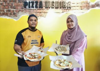 ZULHILMI Yatim dan Umi Nasihah Mat Yusof menunjukkan antara pizza yang dijual di kedainya di Paya Datu, Manir, Kuala Terengganu. - UTUSAN/KAMALIZA.KAMARUDDIN