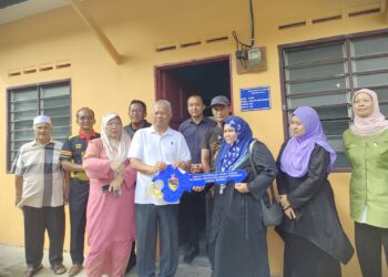 MOHD. Zamri Mohd. Esa menyerahkan replika kunci kepada Yusnita Baharuddin sambil diperhatikan Suhaimi Aini dalam Majlis Penyerahan Rumah PPMS di Kampung Seri Kendong, Rembau hari ini.- UTUSAN/NOR AINNA HAMZAH