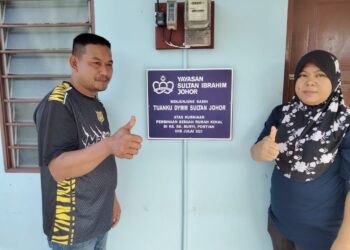 AHMAD SHAH Salim dan Nora Mohd. Noh menunjukkan papan tanda rumah yang disumbangkan oleh YSIJ  di Kampung Sungai Bunyi, Pontian.