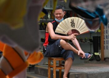 A man cools himself with a fan during a hot day in Hong Kong on September 13, 2022. (Photo by Peter PARKS / AFP)