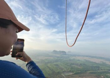 IZZATI Khairudin melihat pemandangan Perlis ketika berada di dalam belon udara panas di Chuping, Perlis semalam.- UTUSAN