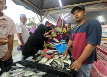 ABDUL Hayie Zakaria (kanan) melayan pembeli ikan harga lelong di Cherang Ruku, Pasir Puteh, Kelantan, semalam. UTUSAN/TOREK SULONG.